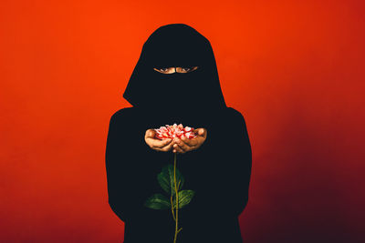 Young woman standing against red background