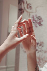 Cropped hands of woman touching mirror at home