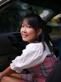 Portrait of young woman sitting in car