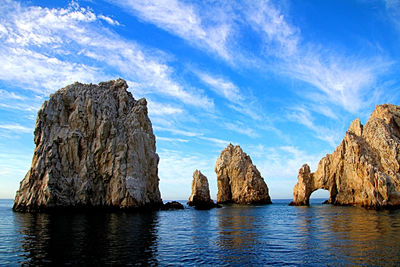 Panoramic view of rock formations in sea against blue sky