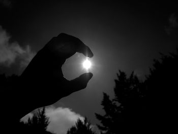 Close-up of hand holding sun during sunset