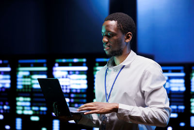 Side view of man using laptop at office