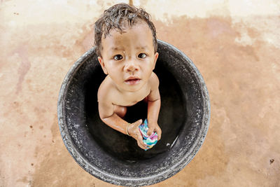 Portrait of cute boy sitting in bucket