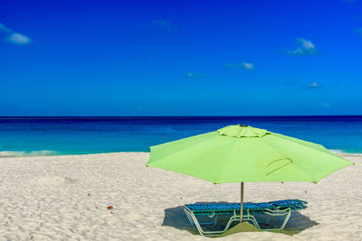 Deck chairs on beach against clear blue sky