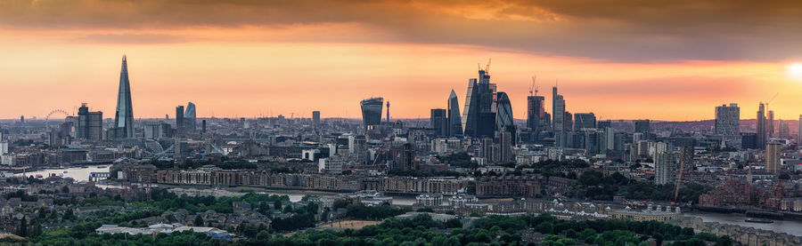 Buildings in city against cloudy sky during sunset