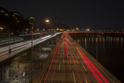 High angle view of light trails on bridge and street by river