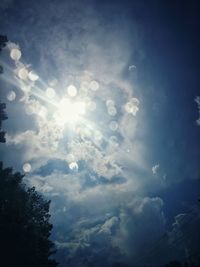 Low angle view of sunlight streaming through clouds