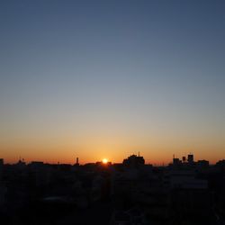 Silhouette cityscape against clear sky during sunset