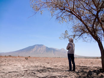 Full length of man standing by tree on field against sky