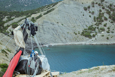 Person holding umbrella on land by sea against mountains