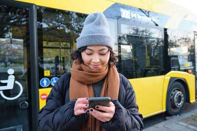 Portrait of smiling young woman standing in city