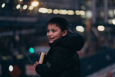 Portrait of smiling man holding illuminated while standing at night