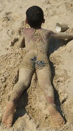 High angle view of boy lying on sandy beach