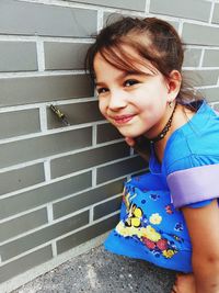 Portrait of smiling girl with butterfly on wall