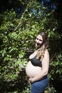 Young woman standing against tree