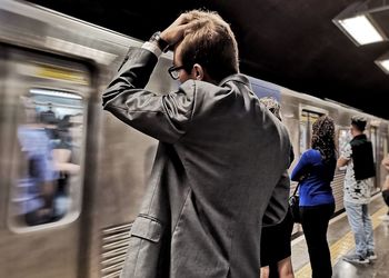 Rear view of man standing on train at railroad station