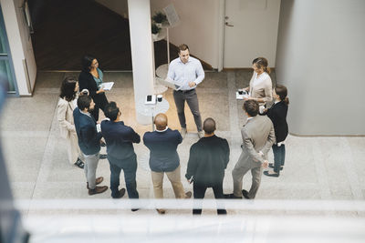 High angle view of male professional with laptop talking to colleagues outside office