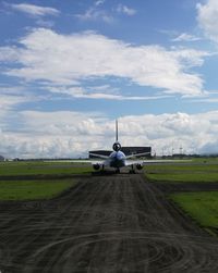 Airplane on airport runway against sky