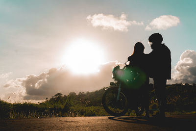 Low angle view of couple standing by motorcycle on land against sky