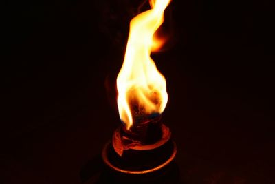 Close-up of lit candle against black background