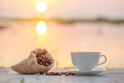 Close-up of coffee cup with sack of coffee beans on table