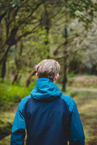 Blond man puts on colourful jacket in rainy  weather. nature fashion style on an athletic figure.