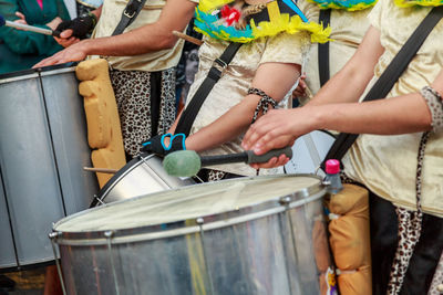 Midsection of women playing drum during festival