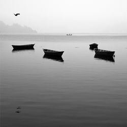 Silhouette boats in sea against clear sky