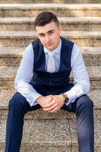 Handsome young groom wearing elegant and stylish dark blue suit outdoors portrait. 