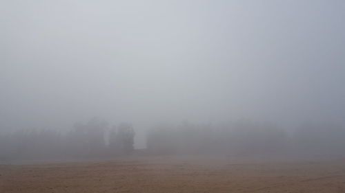 Scenic view of landscape in foggy weather against sky