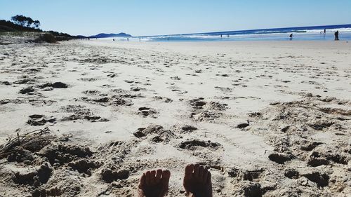 Low section of person on beach against sky