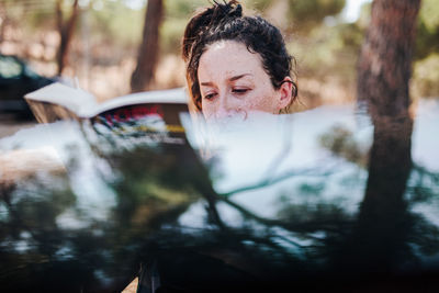 Portrait of woman with reflection of trees in water