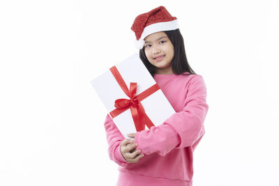 Portrait of a smiling young woman standing against white background
