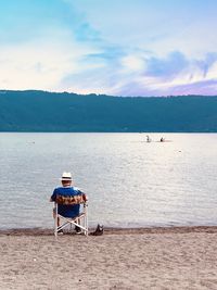 Rear view of man on beach against sky