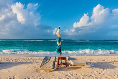 Sunchair on beach against sky