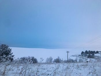 Snow covered field against clear blue sky