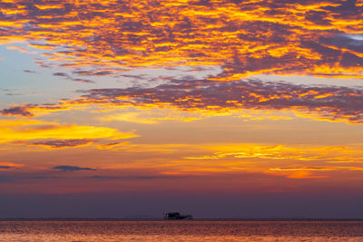 Scenic view of sea against dramatic sky during sunset