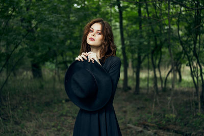 Young woman standing against trees