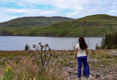 Rear view of woman standing by lake