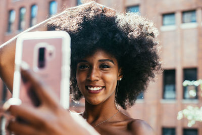Portrait of smiling woman using mobile phone outdoors
