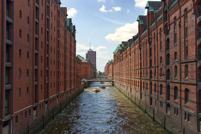 Canal amidst buildings in city against sky