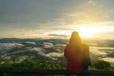 Rear view of man standing against sky during sunset