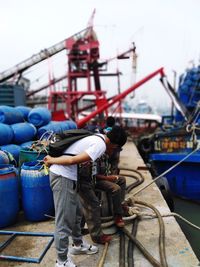 Man working on boat against sky