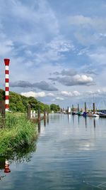 Wooden posts in lake against sky