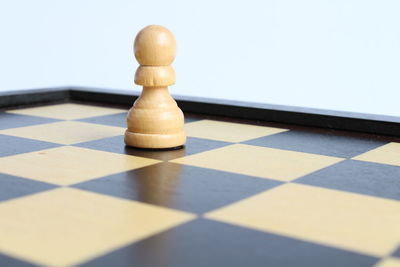 Close-up of pawn on chess board against white background