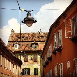 Low angle view of lamp by buildings against sky