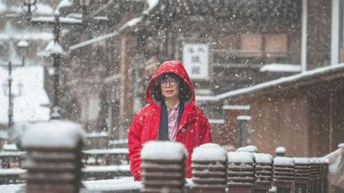 Portrait of smiling young woman standing on snow