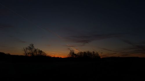 Silhouette trees on field against sky at sunset