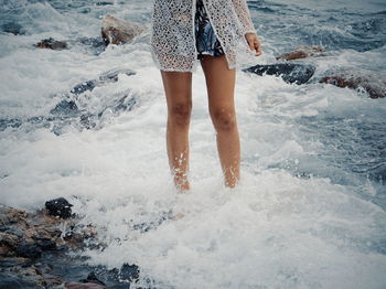 Low section of woman standing at beach