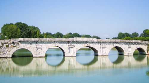 Arch bridge over river against clear sky